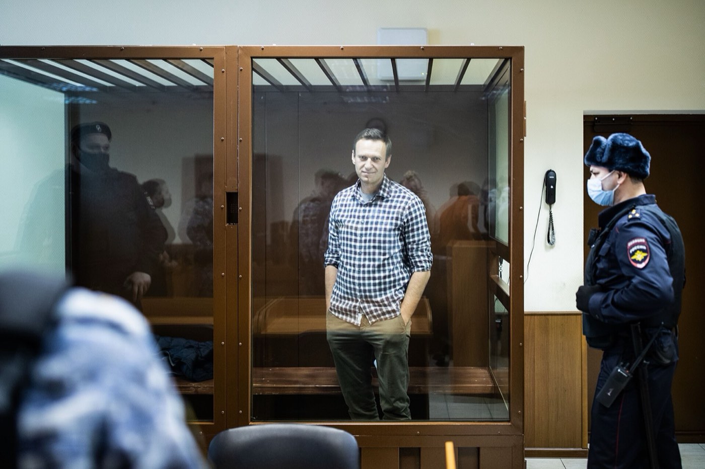 Alexei Navalny in a glass-and-bars cage in a courtroom